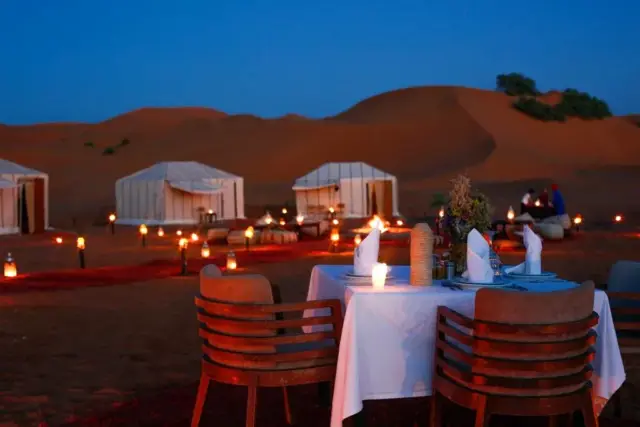 Mesa para dos iluminada con farolillos en las dunas de Merzouga al anochecer